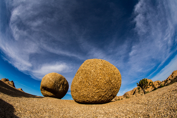 A large and small boulder balancing each other, and an orange desert contrasting a blue sky