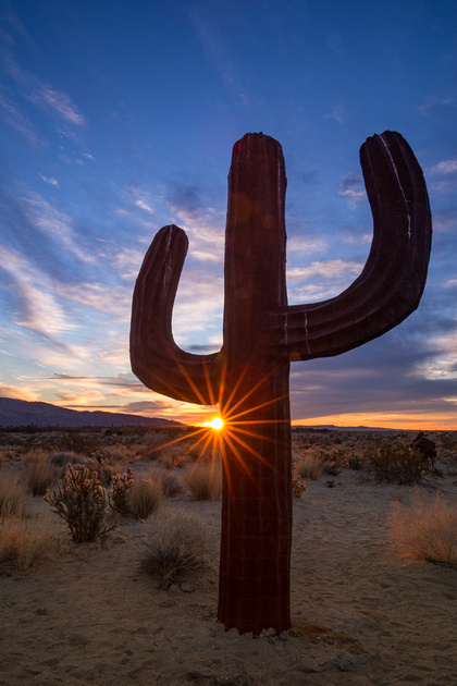 A man made cactus in the middle of a desert sunrise