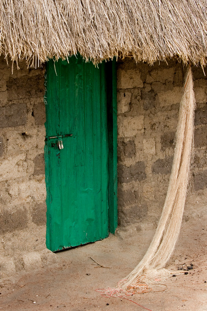 A brightly colored door compared to a muted structure